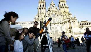 Nenos observando por quenda a través dun refractor diante da catedral de Santiago de Compostela.