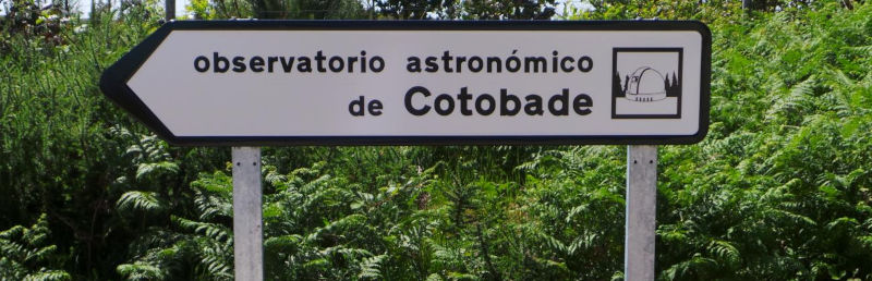 Señal de tráfico indicando observatorio astronómico de Cotobade, contra fondo de helechos